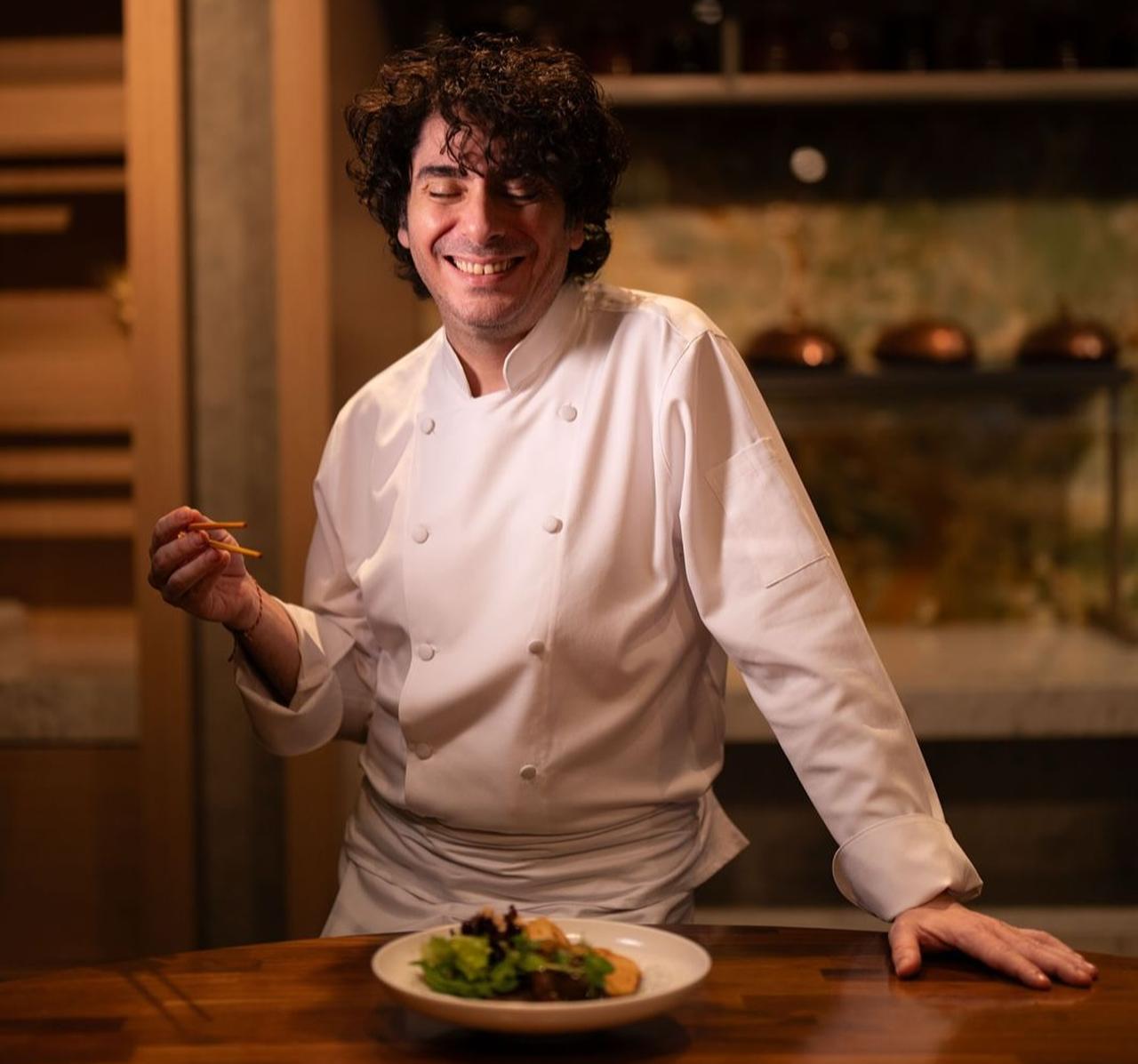 Chef Sinan Damgacioglu smiles while presenting a plated dish at the counter of restaurant, Nov. 6, 2025. (Photo via Instagram/@sinandamgacioglu)
