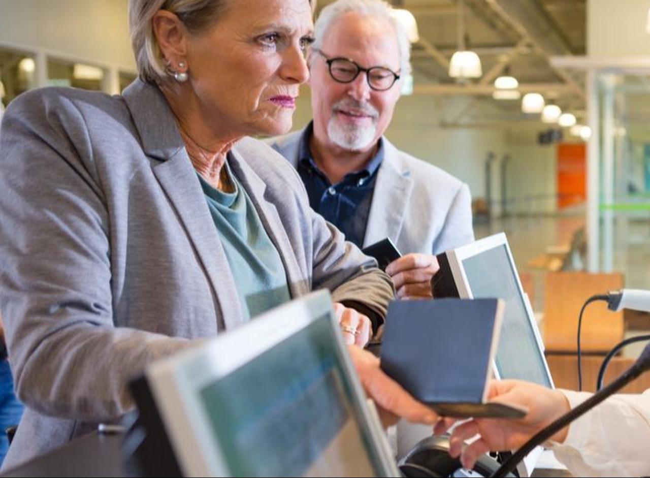 Hotel staff verifying guests' passports during check in procedures. (Adobe Stock Photo)