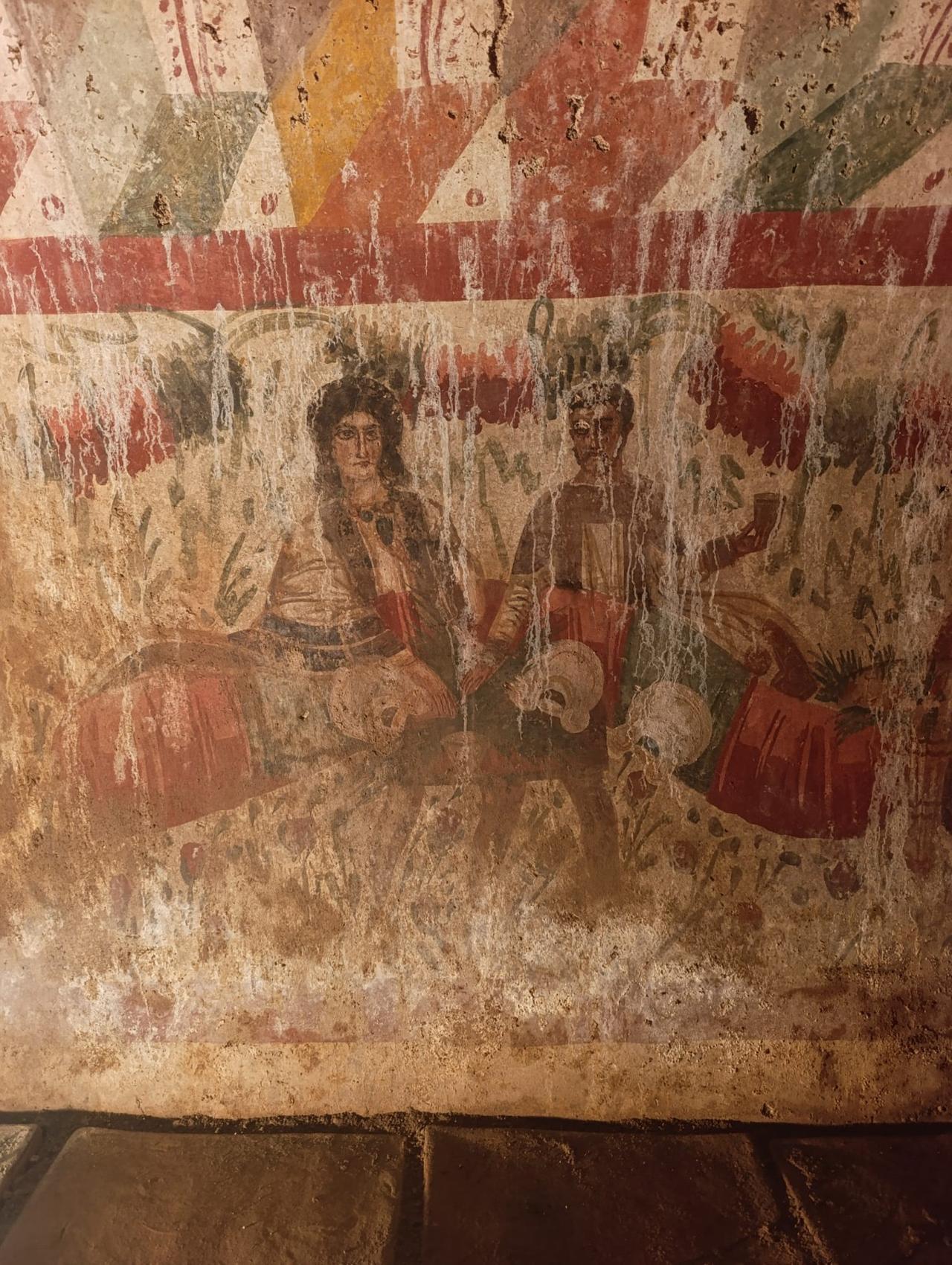 Wall painting inside the Hisardere Necropolis chamber tomb, with two reclining figures shown in a banquet scene against a background of dense floral motifs, Dec. 9, 2025. (Photo via Instagram/@arkeolojihaber)