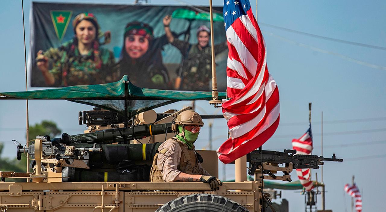 A U.S. armoured vehicle drives past a billboard for the SDF, during a patrol of the Syrian northeastern town of Qahtaniyah at the border with Türkiye, October 31, 2019. (AFP Photo)