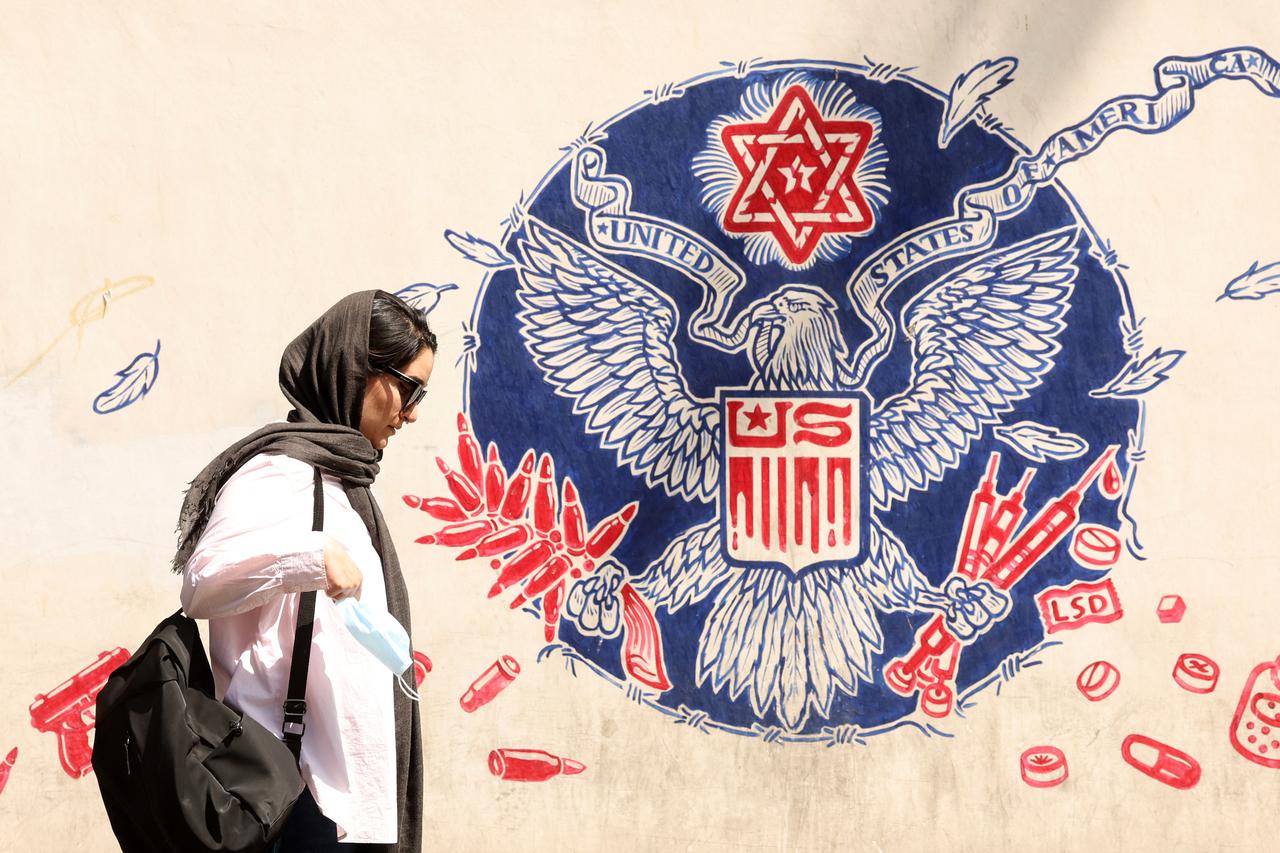 A woman walks past an anti-US mural near the former US embassy in Tehran May 11, 2025.