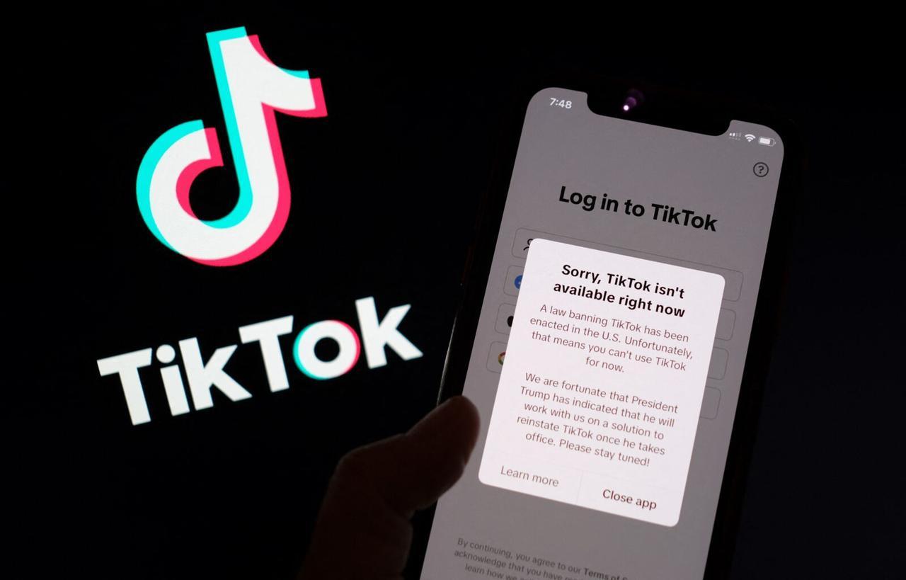 This illustration photo taken in Los Angeles on January 18, 2025, shows the TikTok app on a smartphone screen in front of the TikTok logo. TikTok disconnected access to its users in the United States late January 18 after no action was taken shortly before a national ban was to take effect, in the name of national security, unless its Chinese owners reach a deal to sell it to non-Chinese buyers by January 19, with President-elect Donald Trump unable to intervene until he takes office.  A law banning TikTok has been enacted in the US,  said a message to users attempting to use the app.  Unfortunately, that means you cant use TikTok for now.  (Photo by Chris DELMAS / AFP)