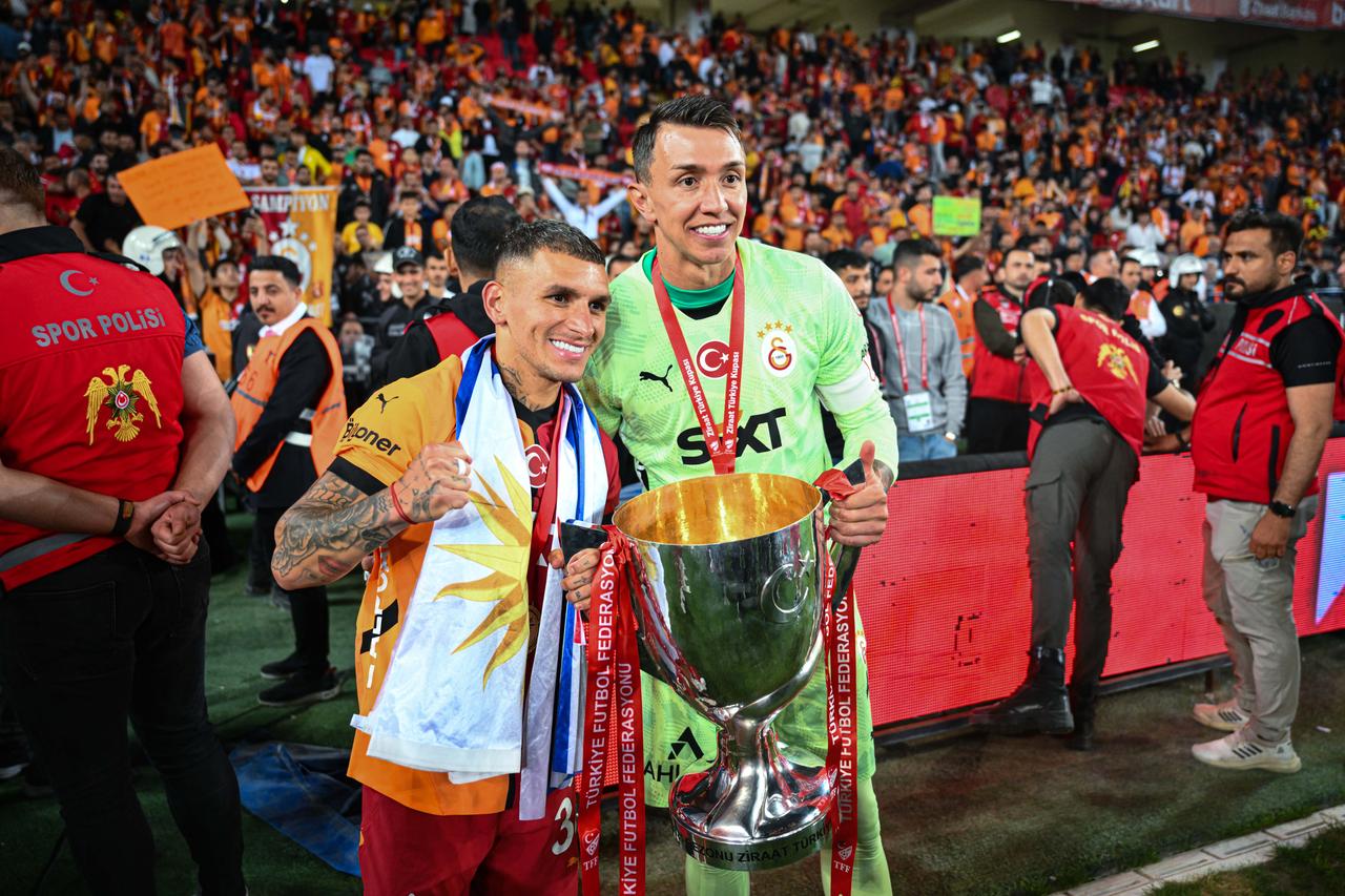 Lucas Torreira and Fernando Muslera pose with the trophy as Galatasaray players celebrate after a 3-0 victory over Trabzonspor in the Ziraat Turkish Cup Final at Gaziantep Metropolitan Municipality Stadium in Gaziantep, Turkiye, on May 14, 2025. (AA Photo)