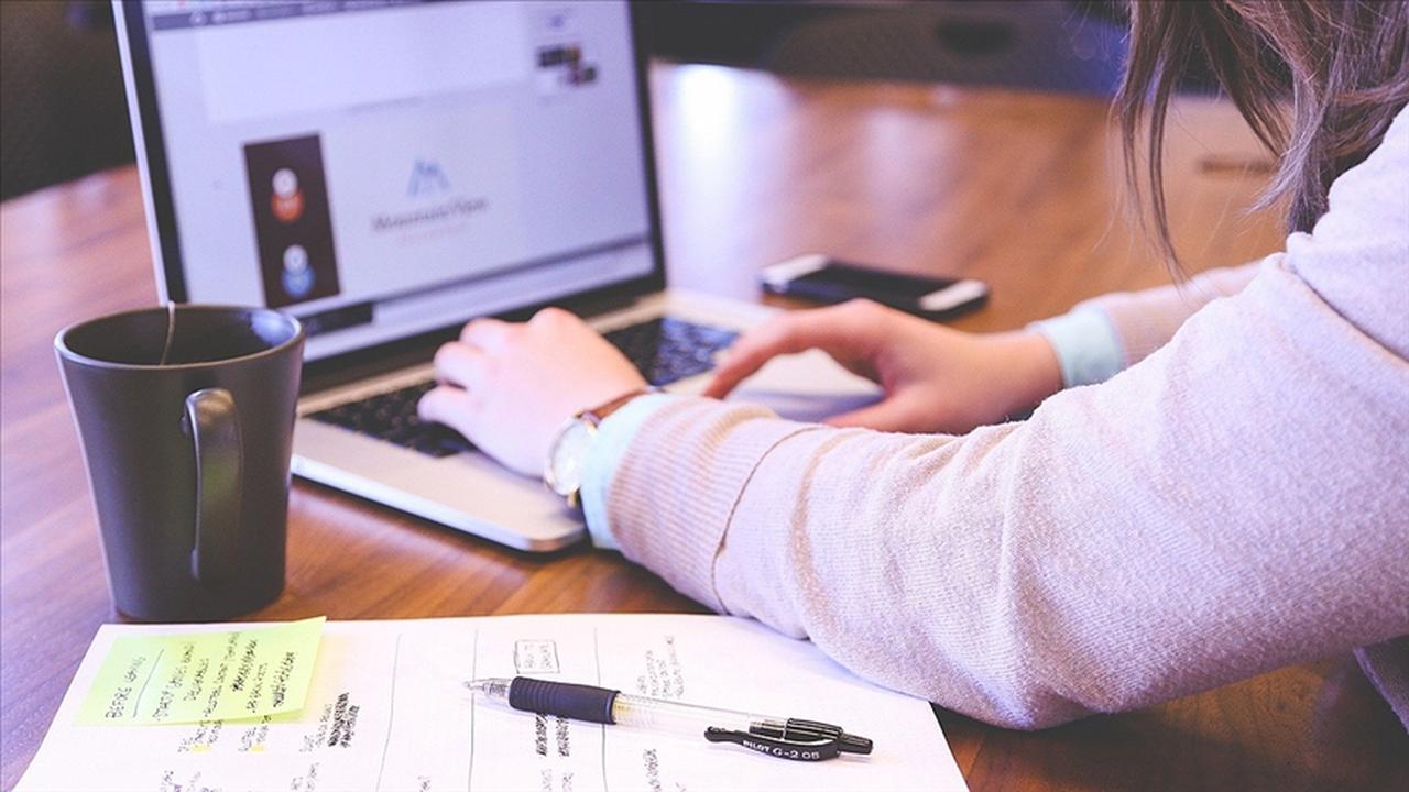 File photo shows a woman working on her laptop at a shared workspace, with job planning notes and a coffee mug beside her, accessed on May 16, 2025. (AA Photo)