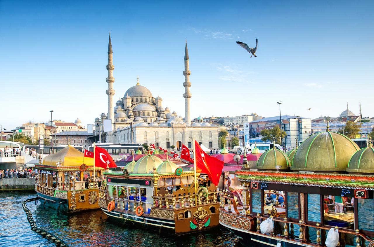 Fishing boats decorated with Turkish flags line the waterfront in Eminonu, with the iconic Suleymaniye Mosque in the background, in Istanbul, Türkiye, on October 6, 2015. (Adobe Stock Photo)