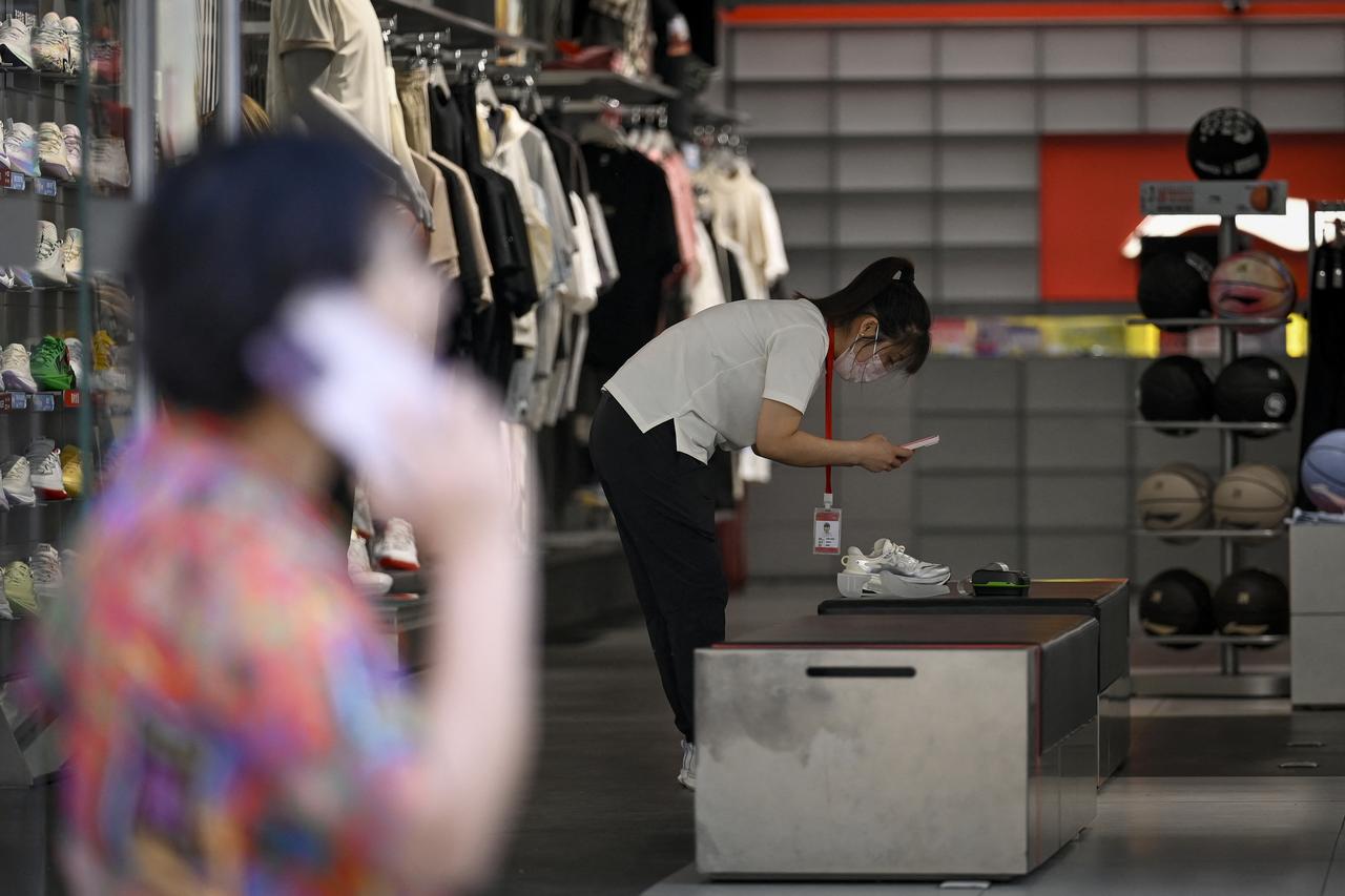 A sales employee checks a pair of shoes at a clothing store in Beijing on May 19, 2025. (AFP Photo)