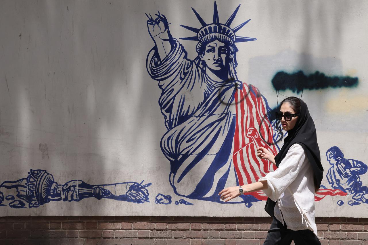 A woman walks past an anti-US mural near the former US embassy in Tehran on May 20, 2025. (AFP Photo)