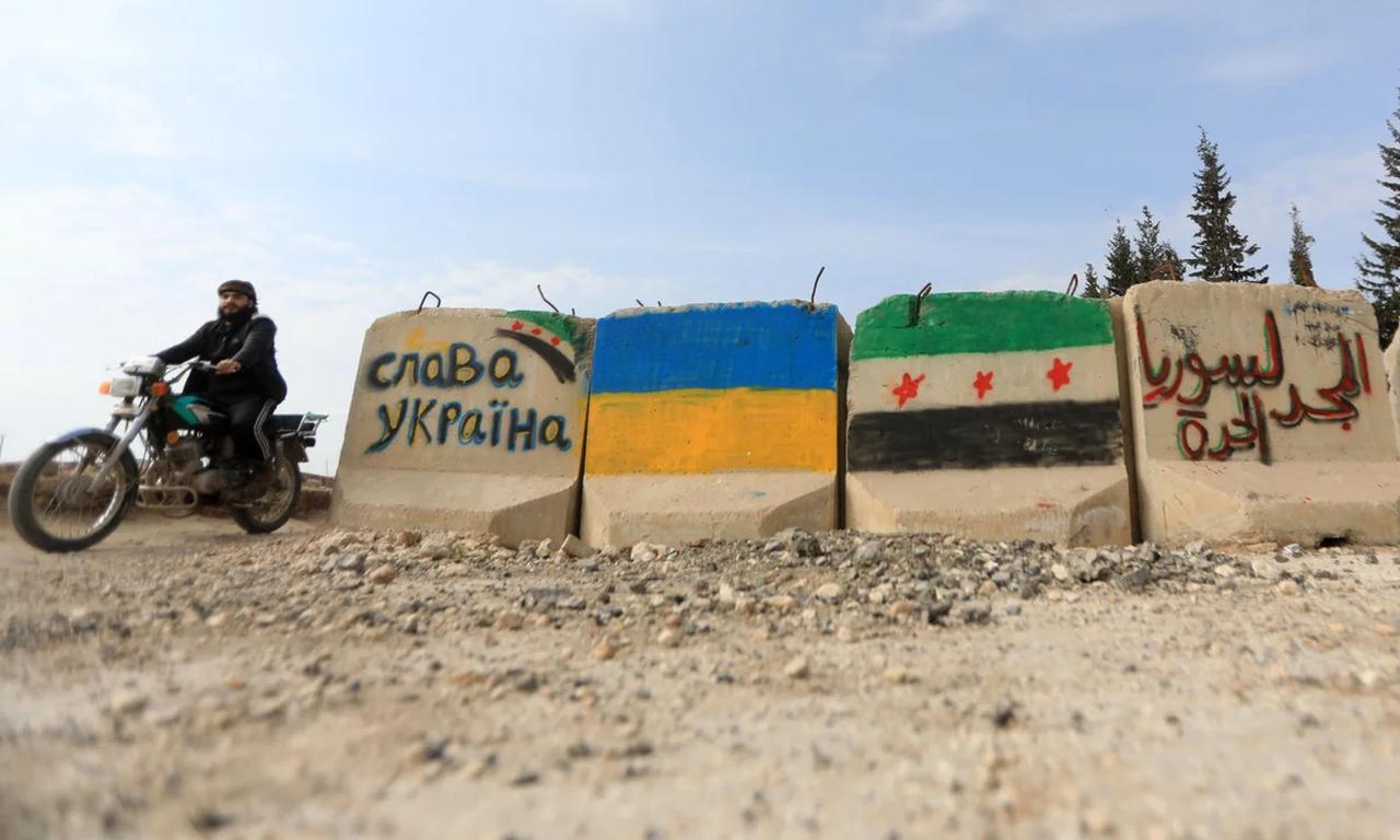 A motorcyclist passes cement blocks painted with flags of Ukraine and the Syrian opposition near the Syrian rebel-held city of al-Bab in Aleppo. (Photo: AFP)