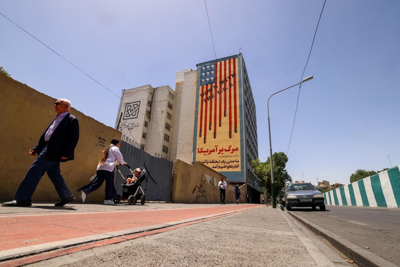 People walk near anti-U.S. mural with the slogan Down with the USA and skulls replacing the stars on the flag, in Tehran, Iran on May 20, 2025. (AFP Photo)