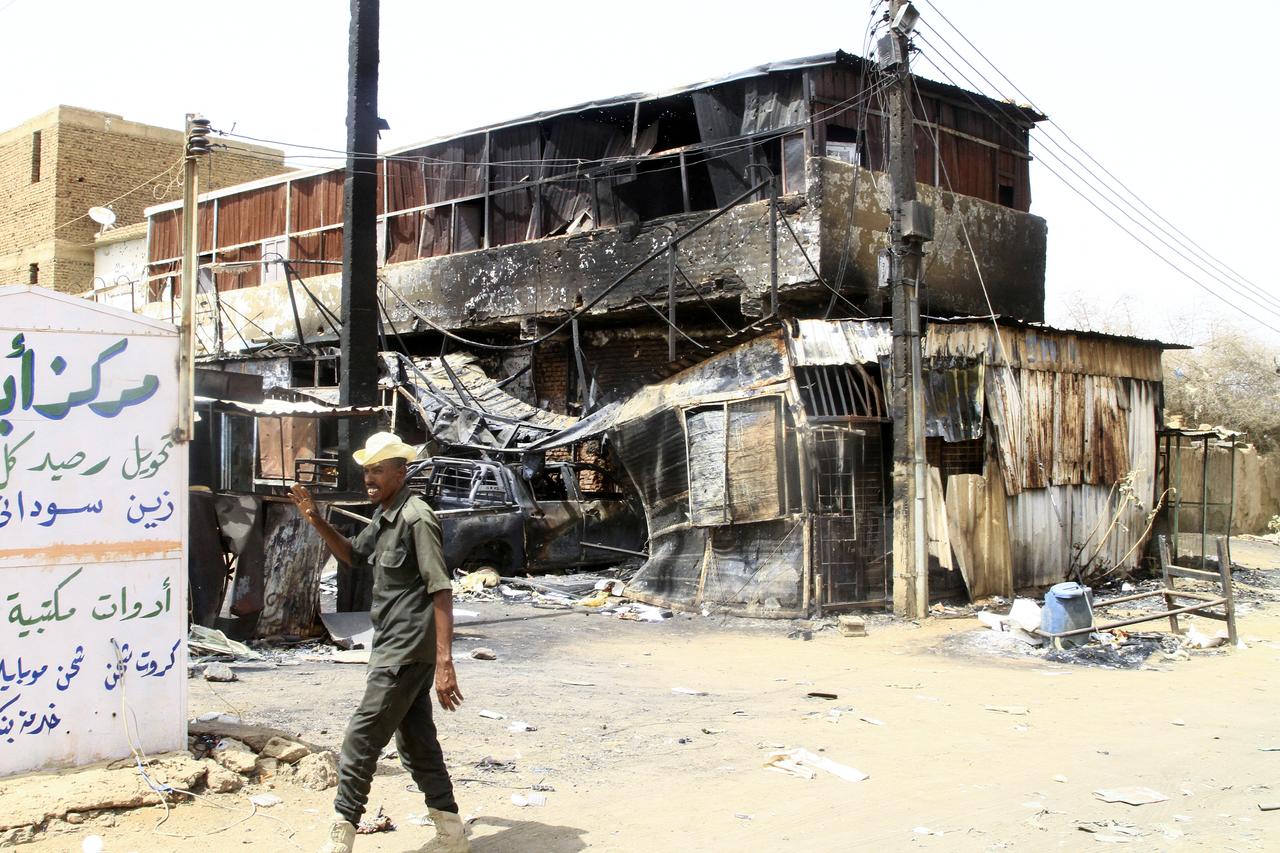 A Sudanese army soldier waves as he walks past a war-damaged building in Salha, south of Omdurman, two days after the Sudanese army recaptured it from the paramilitary Rapid Support Forces (RSF), on May 22, 2025. The Sudanese army said on May 20 that it had dislodged rival paramilitaries from their last positions in Omdurman, part of the Sudanese capital, securing all of Khartoum state nearly two months after recapturing the capitals centre. (Photo by Ebrahim Hamid / AFP)