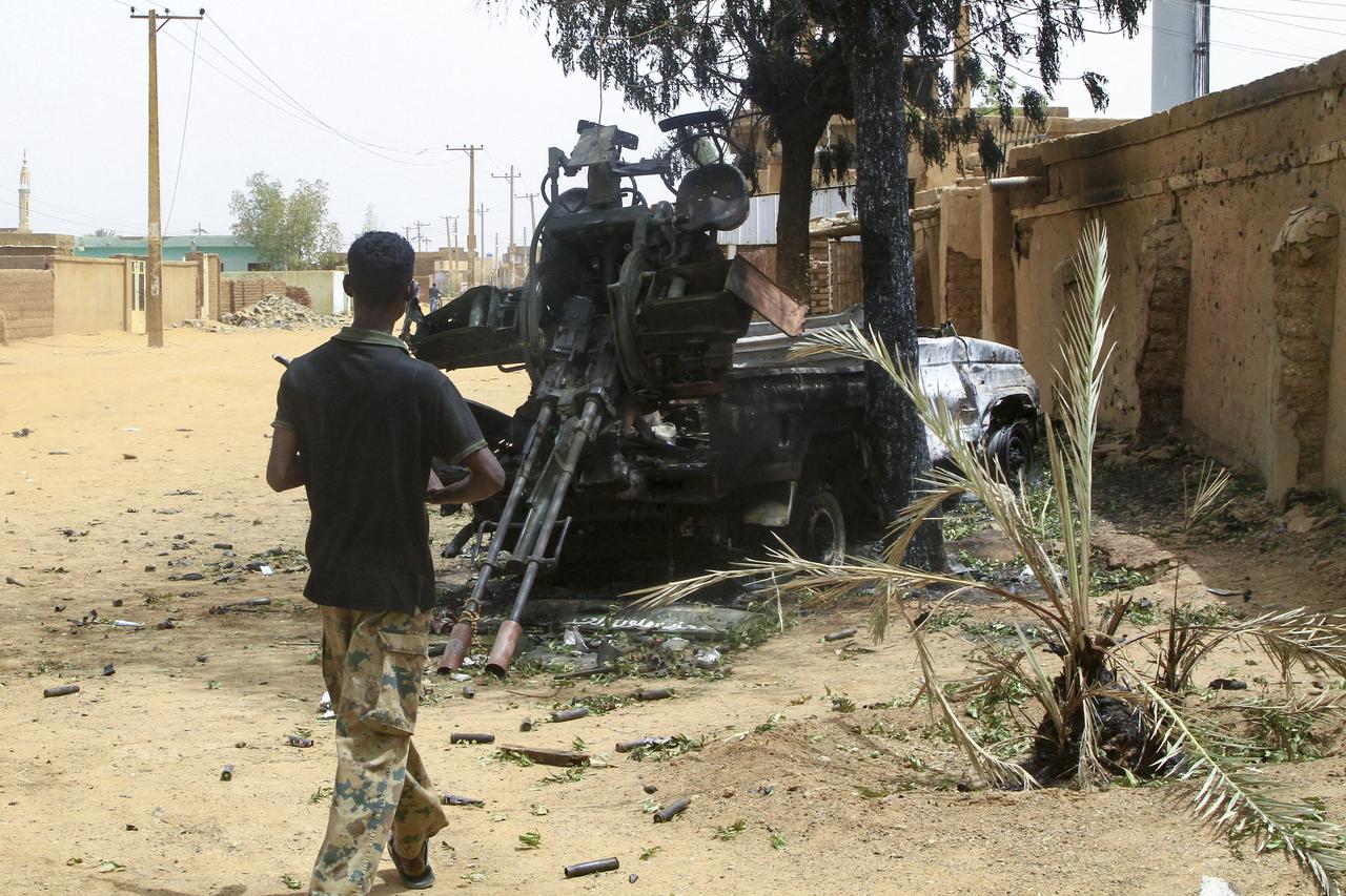 A Sudanese army soldier walks toward a truck-mounted gun left behind by the paramilitary Rapid Support Forces (RSF), in Salha, south of Omdurman, a day after recapturing it from the RSF, on May 21, 2025. The Sudanese army said on May 20 that it had dislodged rival paramilitaries from their last positions in Omdurman, part of the Sudanese capital, securing all of Khartoum state nearly two months after recapturing the capitals centre. (Photo by Ebrahim Hamid / AFP)