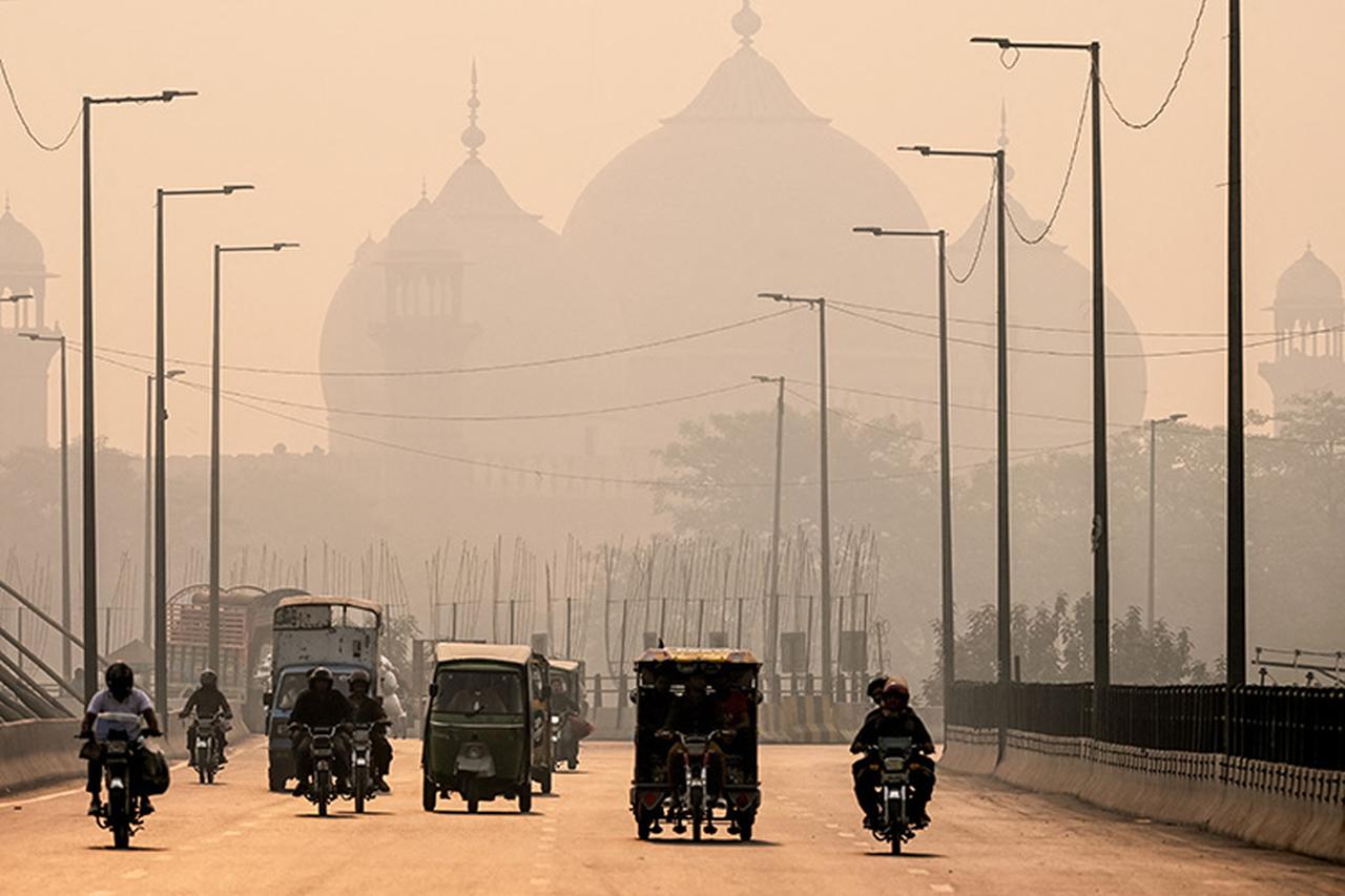 Commuters ride along a street engulfed in smog in Lahore, Pakistan, on 5 November 2024. (AFP Photo)