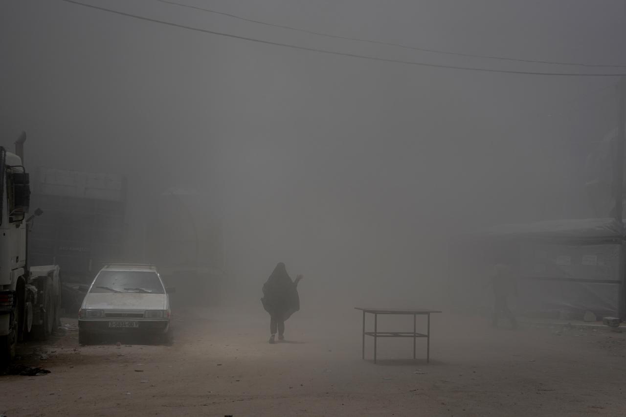 GAZA CITY, GAZA - MAY 23: A woman struggles to find her way through the dust as smoke rises from the Israeli armys attacks on buildings evacuated by displaced Palestinians in the western Gaza Strip, following a warning from the Ansar area on May 23, 2025 in Gaza City, Gaza. ( Anas Zeyad Fteha - Anadolu Agency )
