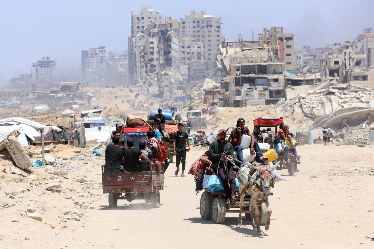 Palestinians transport their belongings as they flee the northern Gaza Strip toward the south, along the coastal al-Rashid road on May 25, 2025. Rescuers in Gaza said eight people were killed and dozens more wounded in Israeli air strikes across the Palestinian territory on May 25. (Photo by Omar AL-QATTAA / AFP)