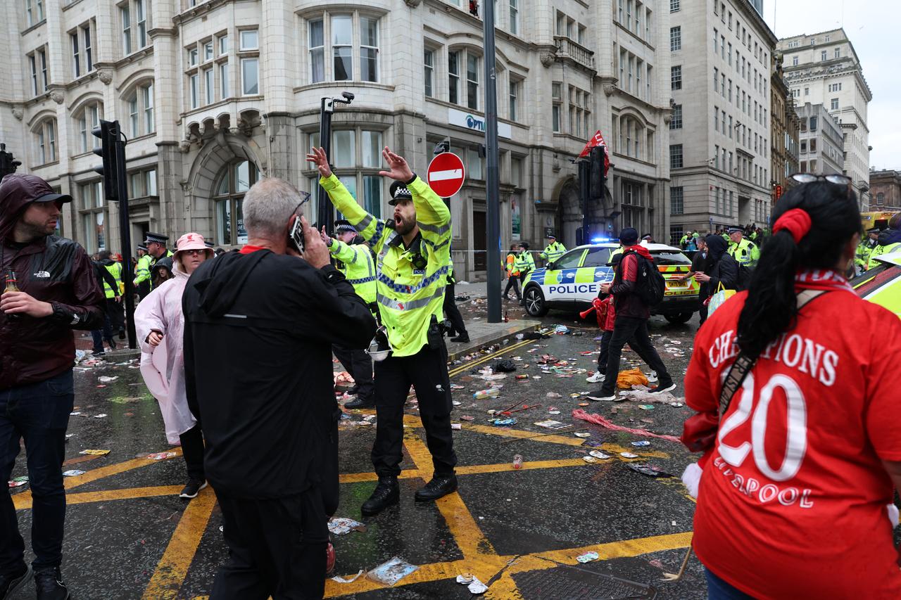 A Police officer shouts at Liverpool fans as he stands on duty a t a Police cordon at the entrance to Water Street, at the scene of an incident, on the sidelines of an open-top bus victory parade for Liverpools Premier League title win, in Liverpool, north-west England on May 26, 2025. (Photo by Darren Staples / AFP)