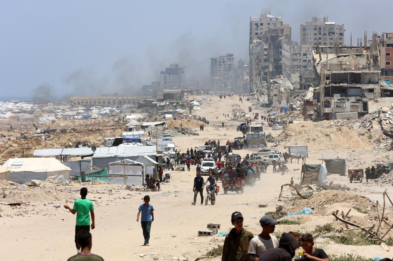 Palestinians transport their belongings as they flee the northern Gaza Strip toward the south, along the coastal al-Rashid road on May 25, 2025. Rescuers in Gaza said eight people were killed and dozens more wounded in Israeli air strikes across the Palestinian territory on May 25. (Photo by Omar AL-QATTAA / AFP)