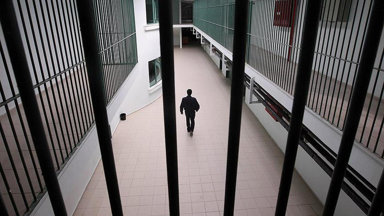 A prison officer is seen walking behind metal bars. (AA Photo)