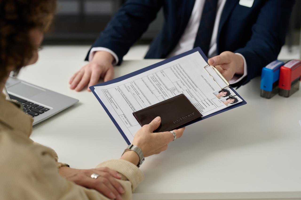 A U.S. visa applicant submits travel documents and a completed application form during an interview at a consulate, accessed on May 27, 2025. (Adobe Stock Photo)