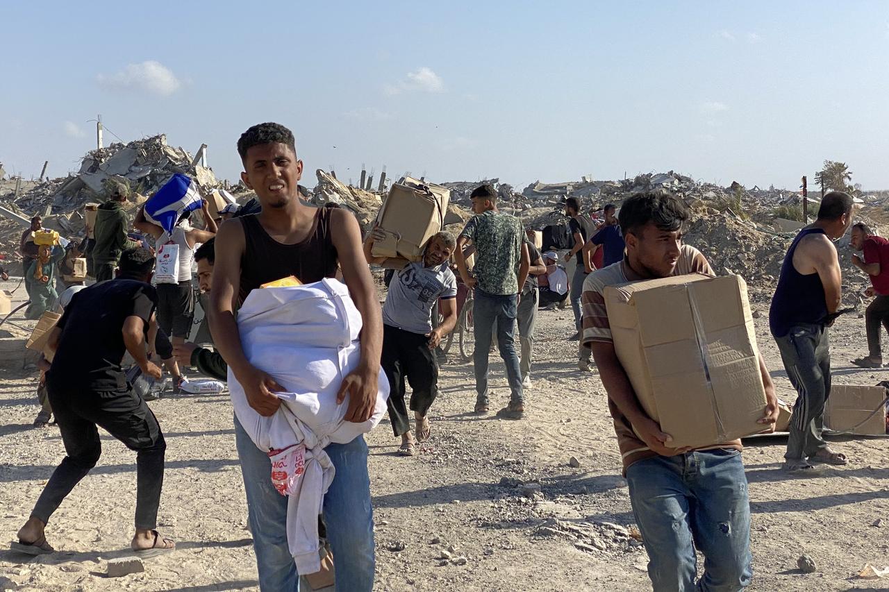 Men look around on alert in the wake of gunfire shots as displaced Palestinians receive food packages from a US-backed foundation pledging to distribute humanitarian aid in western Rafah in the southern Gaza Strip on May 27, 2025. Thousands of Palestinians rushed into a new aid distribution centre run by a US-backed group in southern Gaza on May 27, AFP journalists reported, leading to chaotic scenes as Israel implemented a new distribution system. The incident in Rafah came days after the partial easing of a total aid blockade on the territory that Israel imposed on March 2, leading to severe shortages of food and medicine. (Photo by AFP)