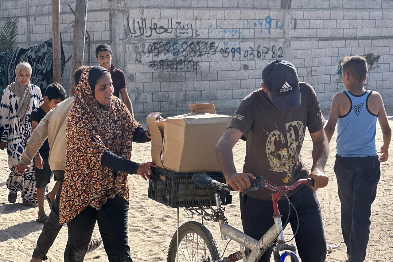 Displaced Palestinians receive food packages from a US-backed foundation pledging to distribute humanitarian aid in western Rafah in the southern Gaza Strip on May 27, 2025. Thousands of Palestinians rushed into a new aid distribution centre run by a US-backed group in southern Gaza on May 27, AFP journalists reported, leading to chaotic scenes as Israel implemented a new distribution system. The incident in Rafah came days after the partial easing of a total aid blockade on the territory that Israel imposed on March 2, leading to severe shortages of food and medicine. (Photo by AFP)