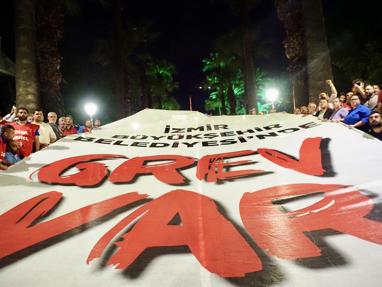 Union members display a large banner reading “Strike at Izmir Metropolitan Municipality” during a nighttime protest marking the start of the labor action in Izmir, Türkiye, on May 29, 2025. (AA Photo)