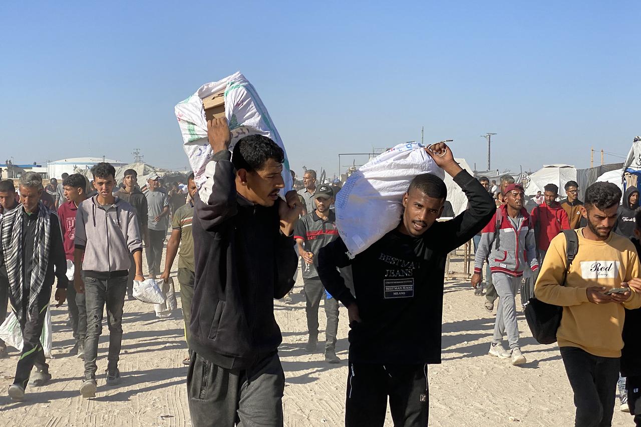 Displaced Palestinians carrying bags of relief supplies return from aid distribution centres in Rafah to their tents in the southern Gaza Strip on May 29, 2025. The humanitarian situation in Gaza, where aid has finally begun to trickle in after a two-month blockade, is dire following 18 months of devastating war between Israel and Palestinian Hamas movement. Food security experts say starvation is looming for one in five people. (Photo by AFP)