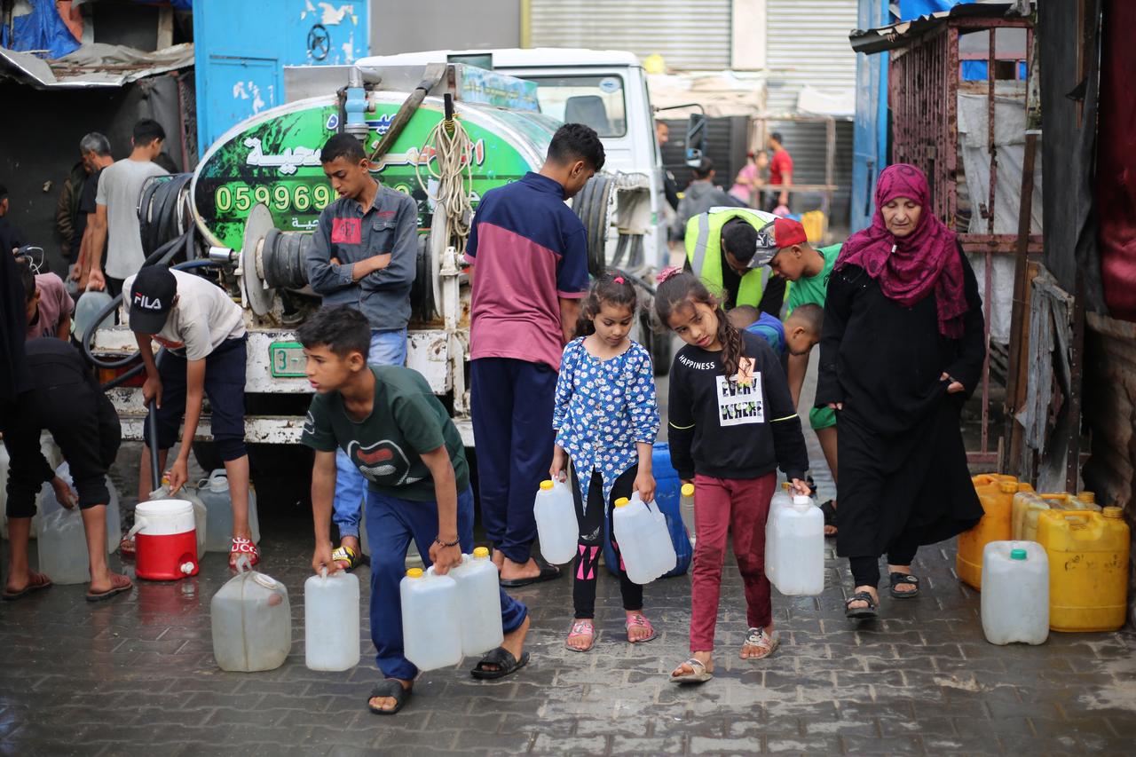 Palestinian children stand over empty containers at a food distribution centre in the Nuseirat camp for refugees, in the central Gaza Strip, on April 30, 2025. (AFP Photo)
