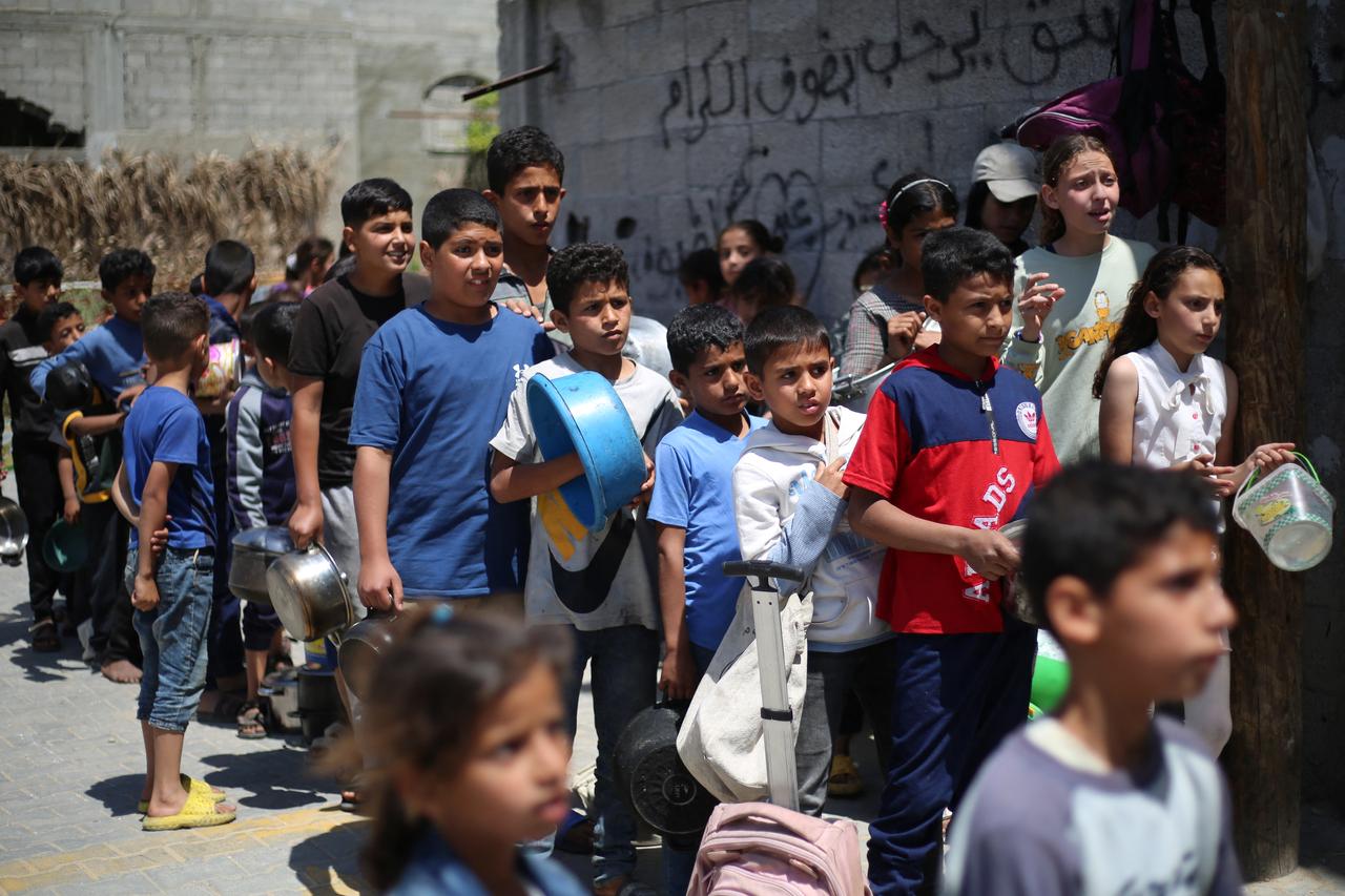 Palestinian children stand over empty containers at a food distribution centre in the Nuseirat camp for refugees, in the central Gaza Strip, on April 30, 2025. (AFP Photo)
