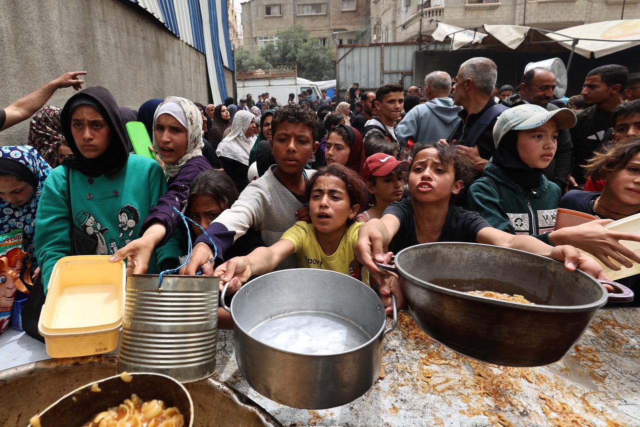 Palestinian children stand over empty containers at a food distribution centre in the Nuseirat camp for refugees, in the central Gaza Strip, on April 30, 2025. (AFP Photo)