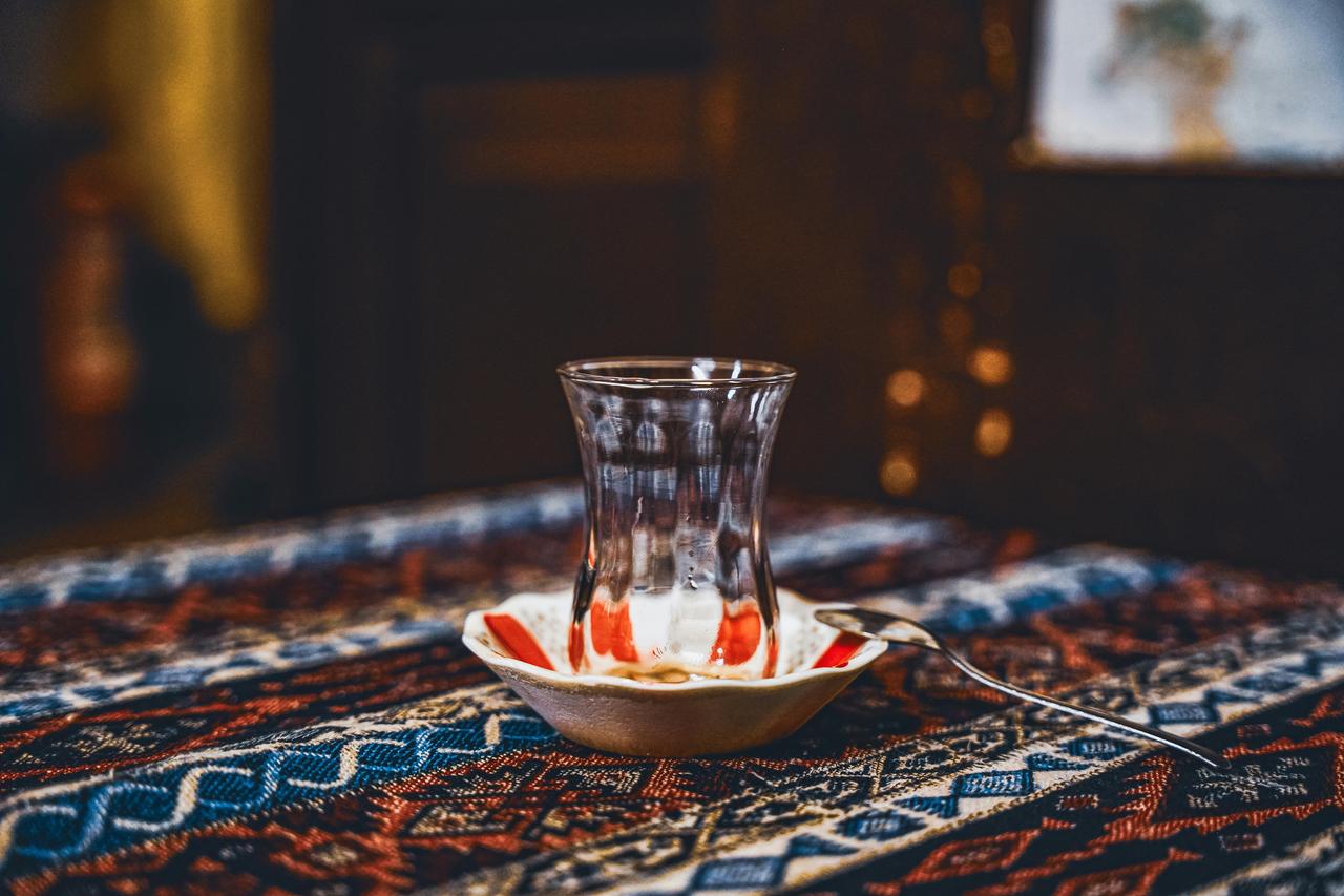 A traditional Turkish tea glass on a patterned tablecloth. (Photo: Bayram Yalcin / Pexels)