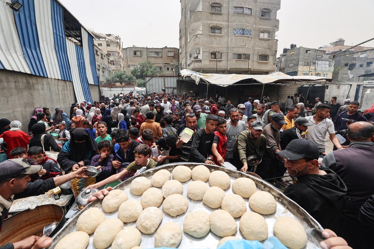 Palestinians queue for a hot meal at a charity kitchen in Gaza City on April 30, 2025. The UN food agency, one of the main providers of food assistance in the besieged Palestinian territory said on April 25 it had "delivered its last remaining food stocks to hot meals kitchens in the Gaza Strip", where Israel has blocked all aid for more than seven weeks, adding "these kitchens are expected to fully run out of food in the coming days". (Photo by Omar AL-QATTAA / AFP)
