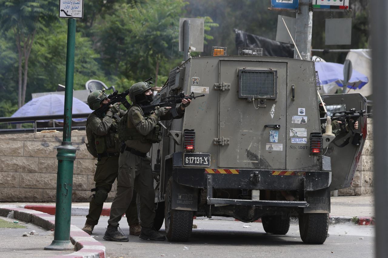 Israeli army soldiers take position during a raid in the heart of the Palestinian city of Nablus, in the occupied West Bank on May 27, 2025. Israeli forces on May 27 raided foreign exchange stores in several West Bank cities including Ramallah and Nablus, accusing their parent company of  connections with terrorist organisations , per an army closure notice. (Photo by Jaafar ASHTIYEH / AFP)