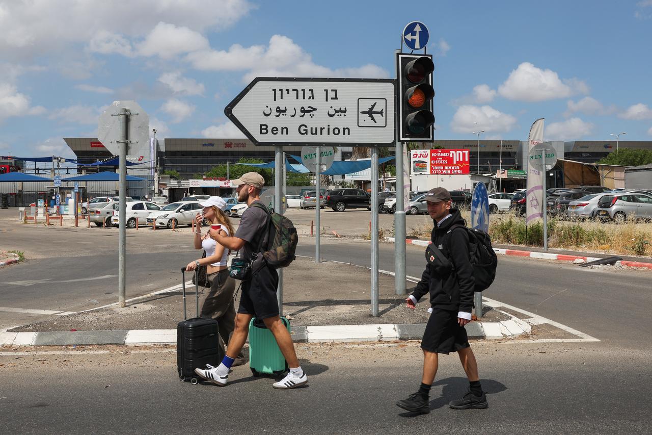 Members of Israeli security services inspect a crater near a road outside Israels Ben Gurion airport after a missile launched from Yemen struck the area on May 4, 2025. A missile launched from Yemen struck near Israels main international airport on May 4, Israeli authorities said, an attack that briefly halted air traffic and triggered threats of retaliation. (Photo by Jack GUEZ / AFP)