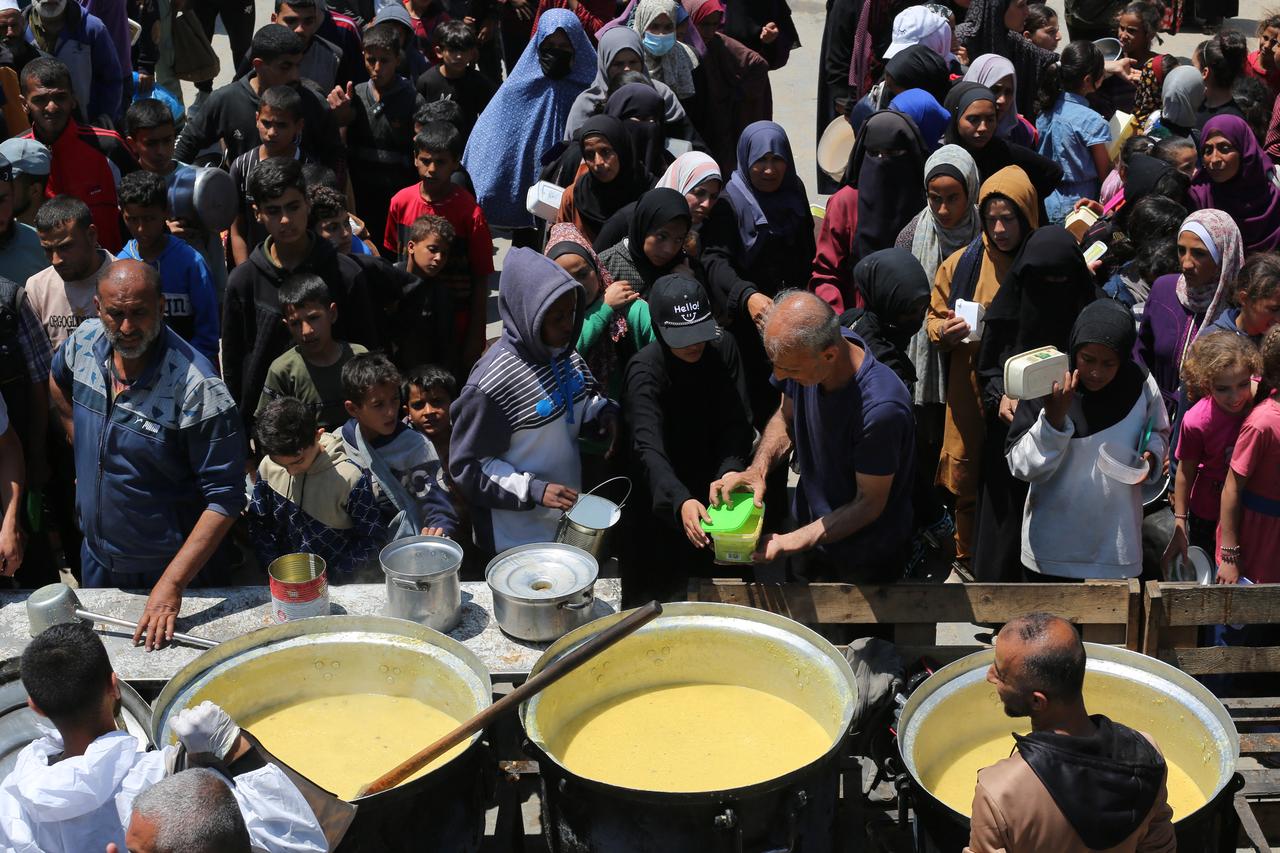Israeli soldiers look on as Palestinians carry their belongings after being ordered to leave their homes during an Israeli operation in the Tulkarem camp for refugees in the northwest of the occupied West Bank on May 2, 2025. (Photo by Jaafar ASHTIYEH / AFP)