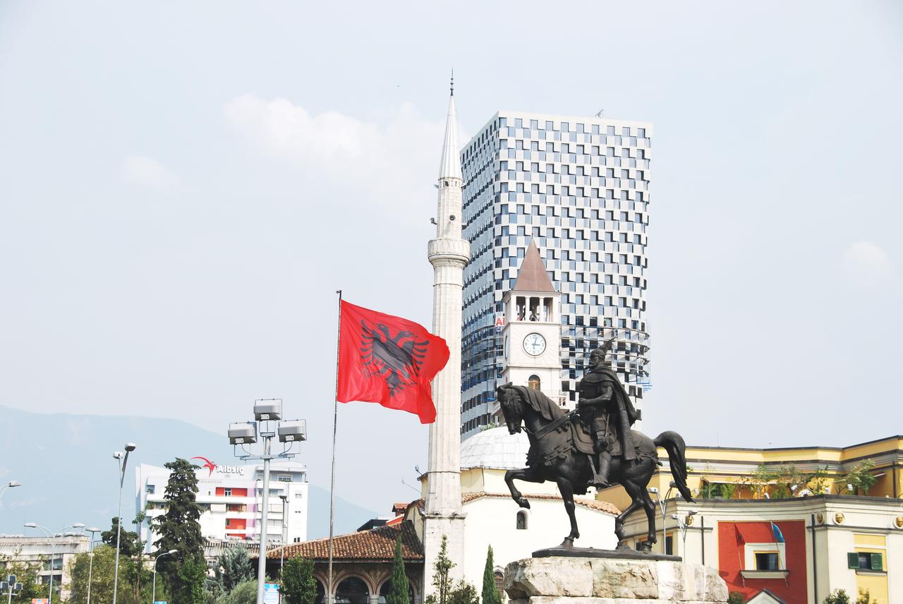 Skanderbeg Square with equestrian statue of Skanderbeg, with Albanian flag, Clock Tower, Mosque mixing with modern architecture concept of history culture on Tirana, Albania on n 16 August 2013. (Adobe Stock Photo)