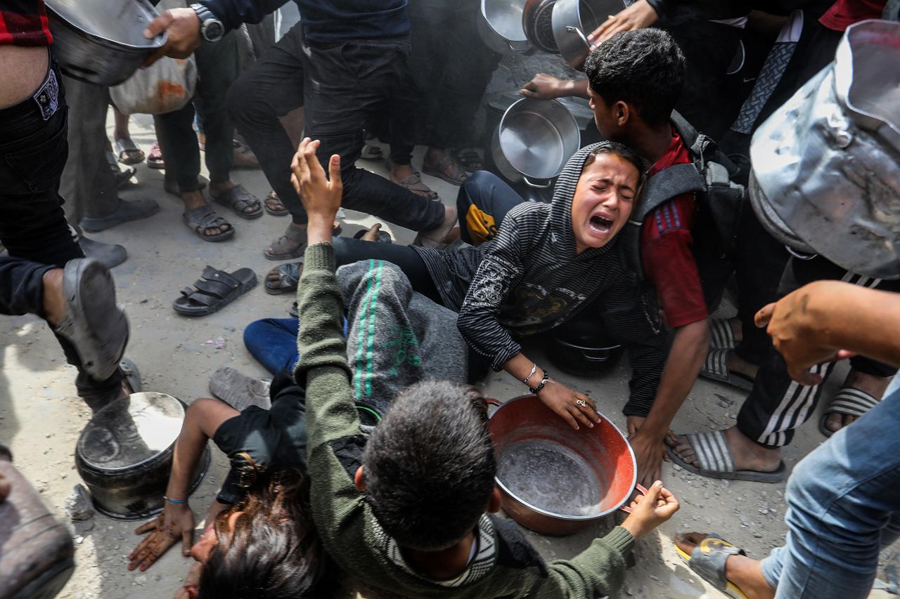 Palestinians, holding pan including children, create a stampede to get hot meals, distributed by charitable organizations to displaced Palestinians amid Israeli attacks in Khan Yunis, Gaza on May 6, 2025. (AA Photo)