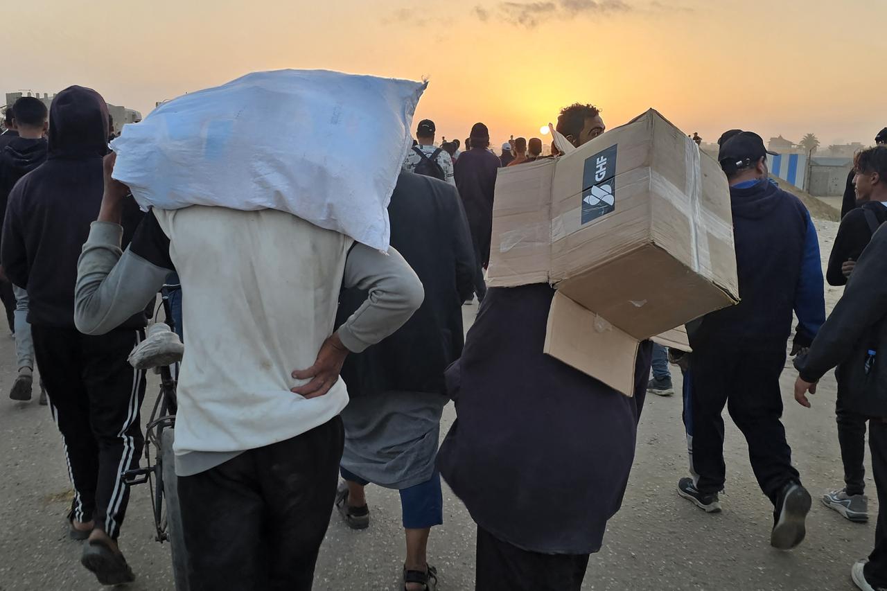 A youth carries an empty box of relief supplies from the Gaza Humanitarian Foundation (GHF), a private US-backed aid group that has bypassed the longstanding UN-led system in the territory, as displaced Palestinians walk near a food distribution centre in Rafah in the southern Gaza Strip on June 1, 2025. Gaza rescuers said Israeli gunfire killed at least 10 Palestinians near a US-backed aid distribution site on June 1, shortly after Washington rejected a Hamas ceasefire proposal as  totally unacceptable . (Photo by AFP)