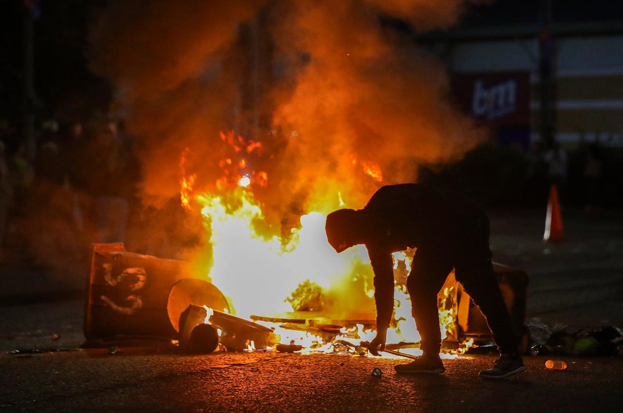 A masked protestor stands by burning bins on fire in a road during a thrid night of anti-immigration demonstrations in Ballymena, Northern Ireland, on June 11, 2025. (AFP Photo)