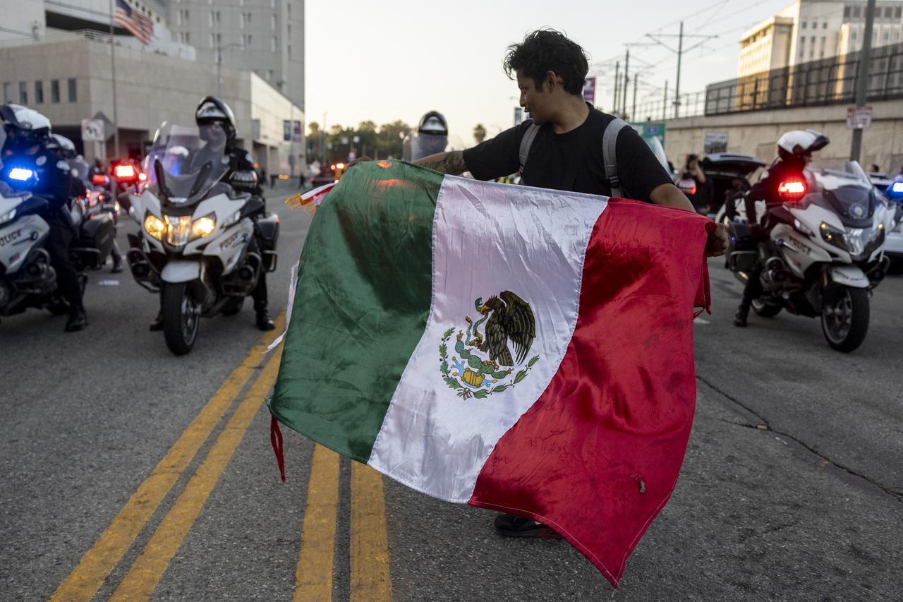 A demonstrator waves a Mexican flag in front of Los Angeles Police (LAPD) officer on motorbikes in front of the Metropolitan Detention Center as protests continue in response to federal immigration operations in Los Angeles on June 13, 2025. (AFP Photo)