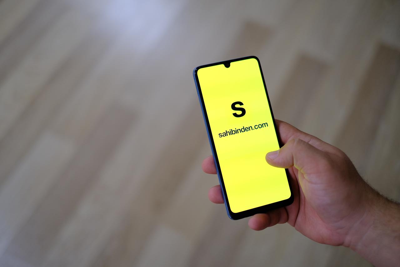 Photo shows a person holding a smartphone and the Sahibinden.com app logo on the phone screen, accessed on June 14, 2025. (Adobe Stock Photo)