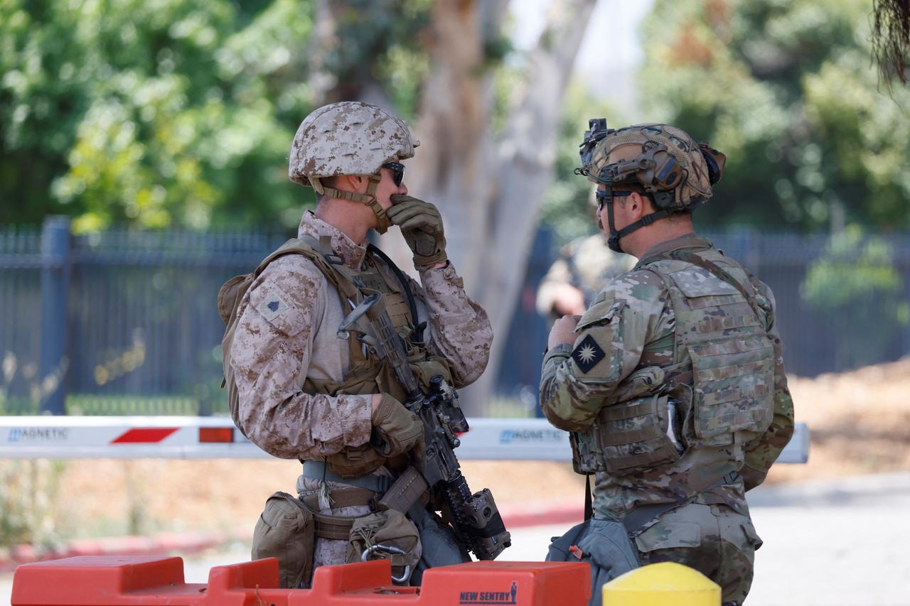 A US Marine (L) chats with a member of the National as they guard the parking lot of the Wilshire Federal Building in Los Angeles, California, on June 13, 2025. (AFP Photo)