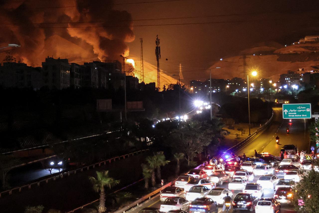 Vehicles jam a highway as a fire blazes nearby in the oil depots of Shahran, northwest of Tehran, Iran on June 15, 2025. (AFP Photo)
