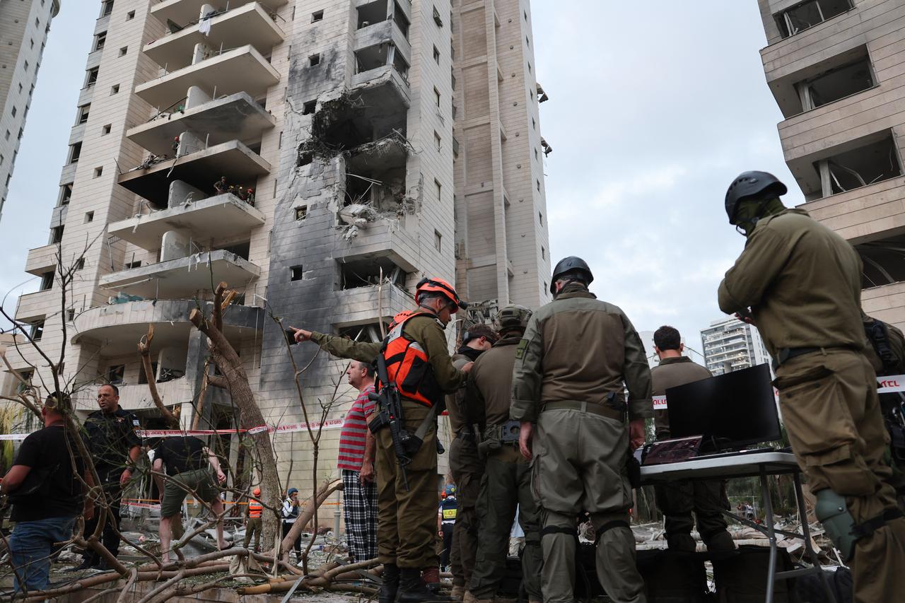 Responders are seen next to a damaged building following a strike by an Iranian missile in the Israeli city of Petah Tikva, east of Tel Aviv, on June 16, 2025. (AFP Photo)