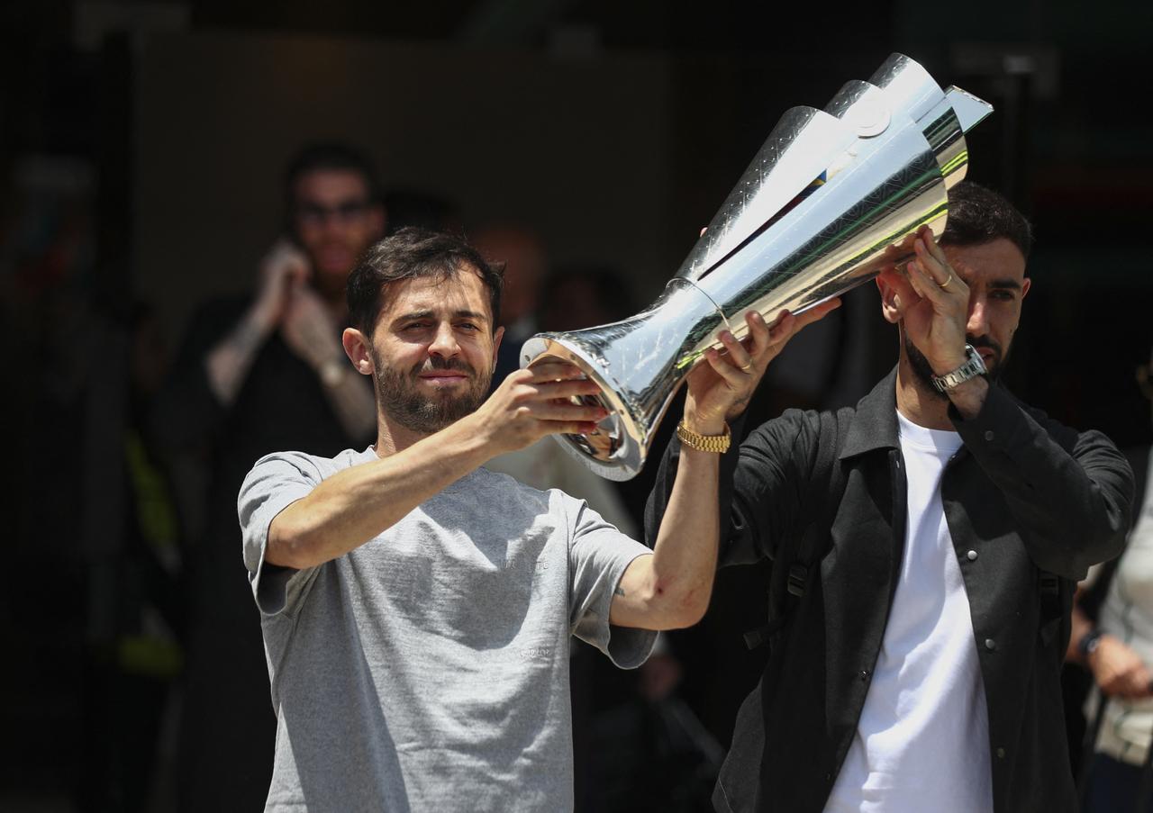 Portugal's midfielders Bruno Fernandes (R) and Bernardo Silva pose with the trophy as they arrive at Lisbon's airport on June 9, 2025. (AFP Photo)