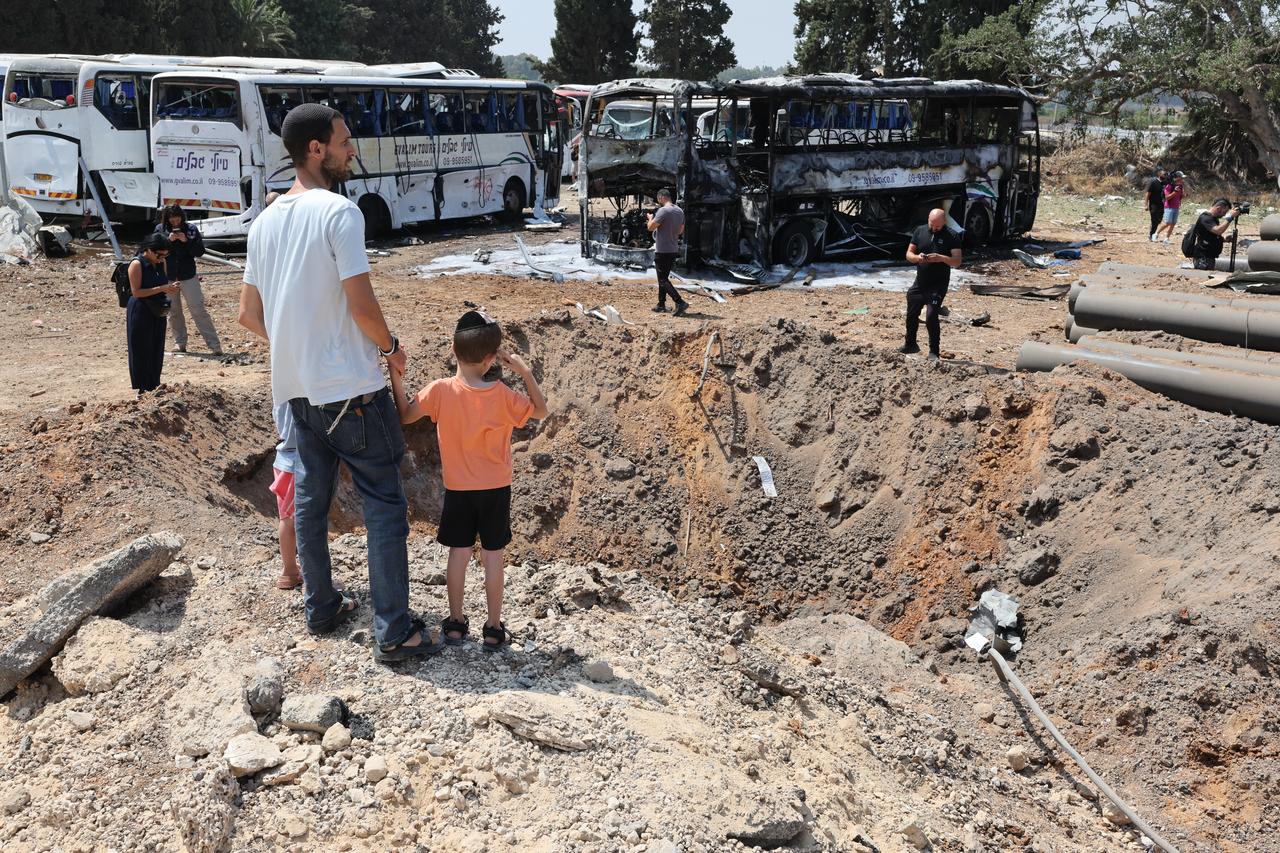 Onlookers stand in front of a huge crater at the impact site of an Iranian missile at a bus depot in Herzliya near Tel Aviv on June 17, 2025. (AFP Photo)