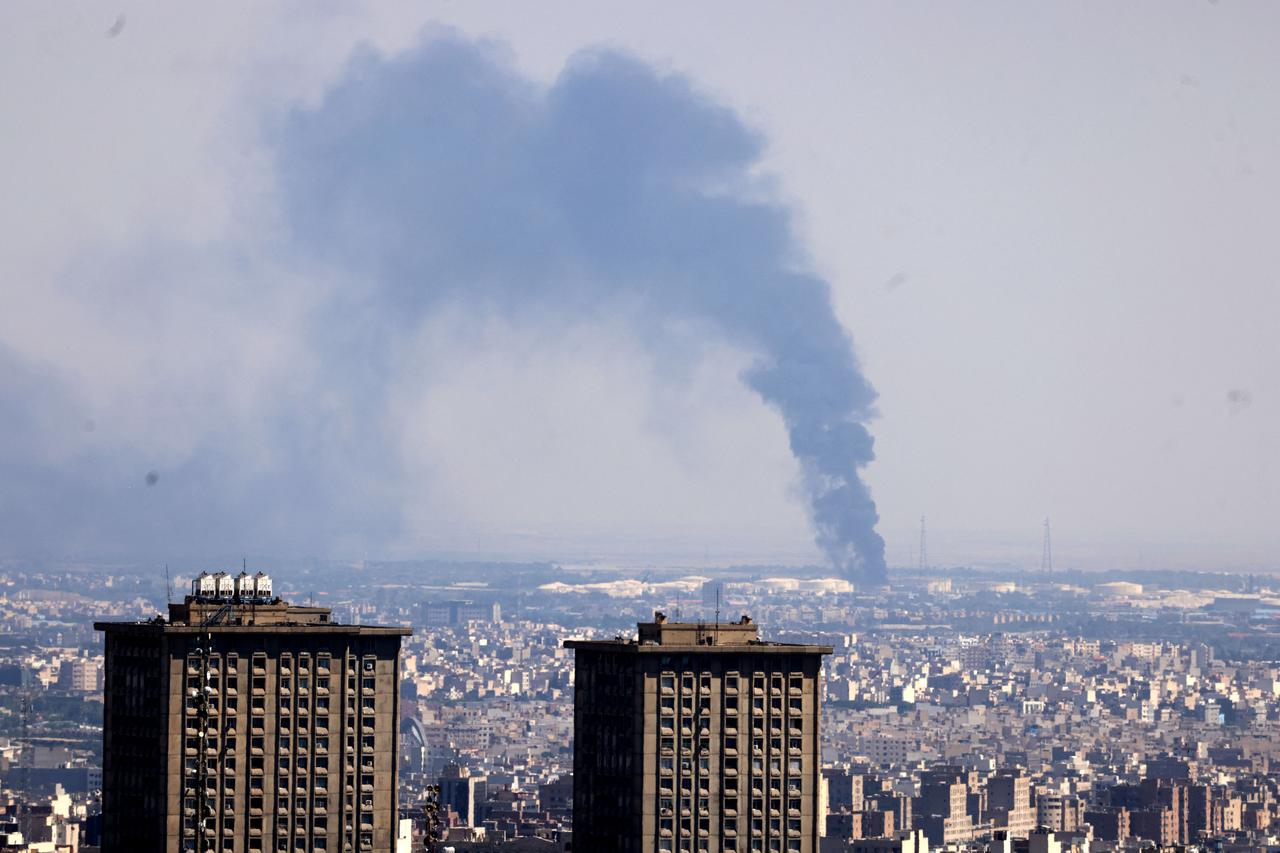 Smoke billows in the distance from an oil refinery following an Israeli strike on the Iranian capital Tehran on June 17, 2025. Israel and Iran exchanged fire again, the fifth day of strikes in their most intense confrontation in history, fuelling fears of a drawn-out conflict that could engulf the Middle East. (Photo by ATTA KENARE / AFP)