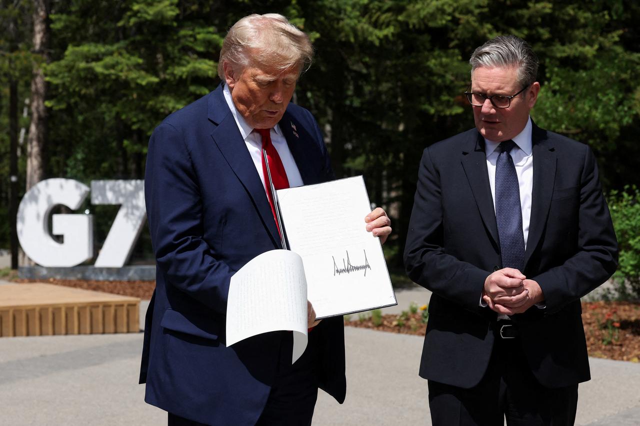 US President Donald Trump (L) holds a signed US-UK trade deal next to British Prime Minister Keir Starmer as they speak to reporters during the Group of Seven (G7) Summit at the Pomeroy Kananaskis Mountain Lodge in Kananaskis, Alberta, Canada on June 16, 2025. (AFP Photo)