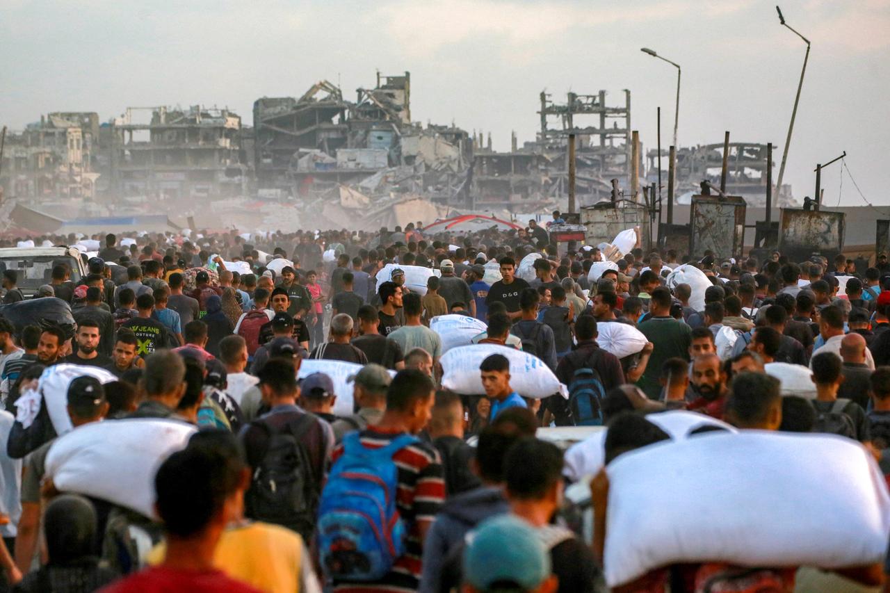 People carrying sacks of flour walk along al-Rashid street in western Jabalia on June 17, 2025, after humanitarian aid trucks reportedly entered the northern Gaza Strip through the Israeli-controlled Zikim border crossing. (AFP Photo)