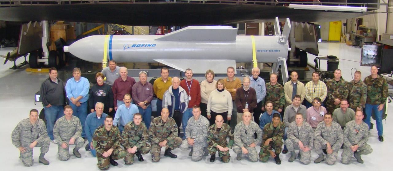 Weapon specialists gather in front of a mock up of the Massive Ordnance Penetrator and the B-2 weapons load trainer at Whitman Air Force Base, Missouri, U.S., Dec. 18, 2024. (U.S. Air Force Photo)