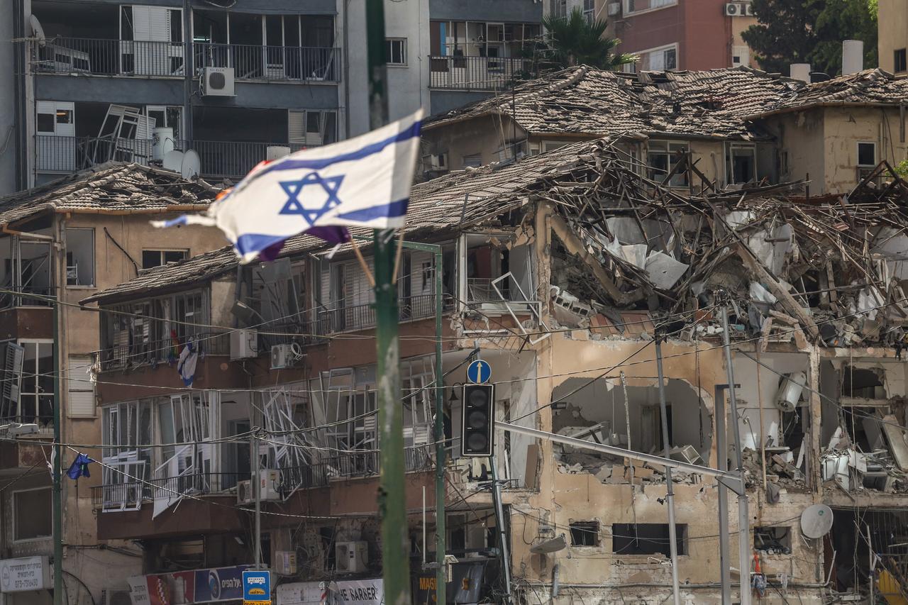 The Israeli flag flutters in front of a destroyed building at the site of an Iranian missile attack in Ramat Gan in central Israel near Tel Aviv, on June 19, 2025. (AFP Photo)